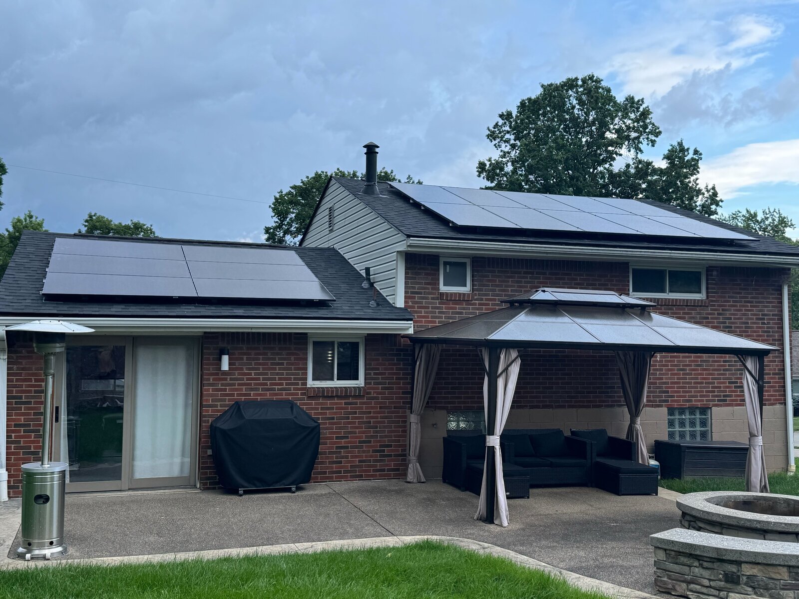 Brick home with rooftop solar panels and a covered back patio