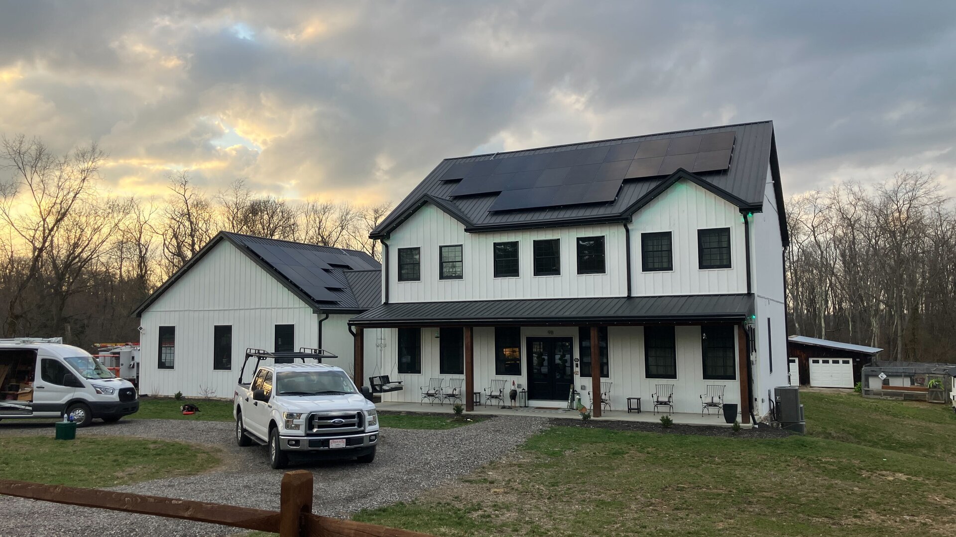 Modern white farmhouse with rooftop solar panels and a Lifestyle Solar work truck in the driveway