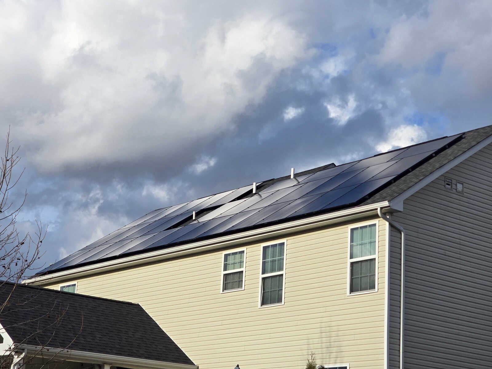 Two-story home with rooftop solar panels under a dramatic blue sky